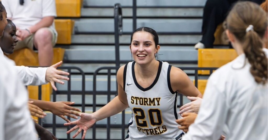 A women's basketball player reaches out to high-five her teammates