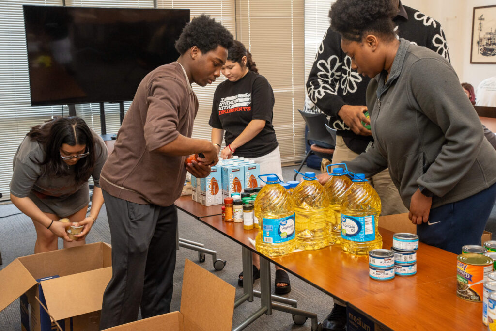 Student volunteers grouping non-perishable food items and packing them into boxes.