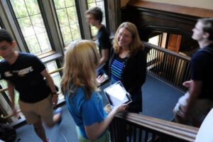 A professor smiling at a student in the stairway as students pass by them