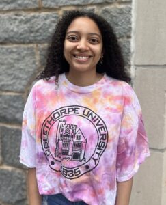 A student stands in front of a wall.