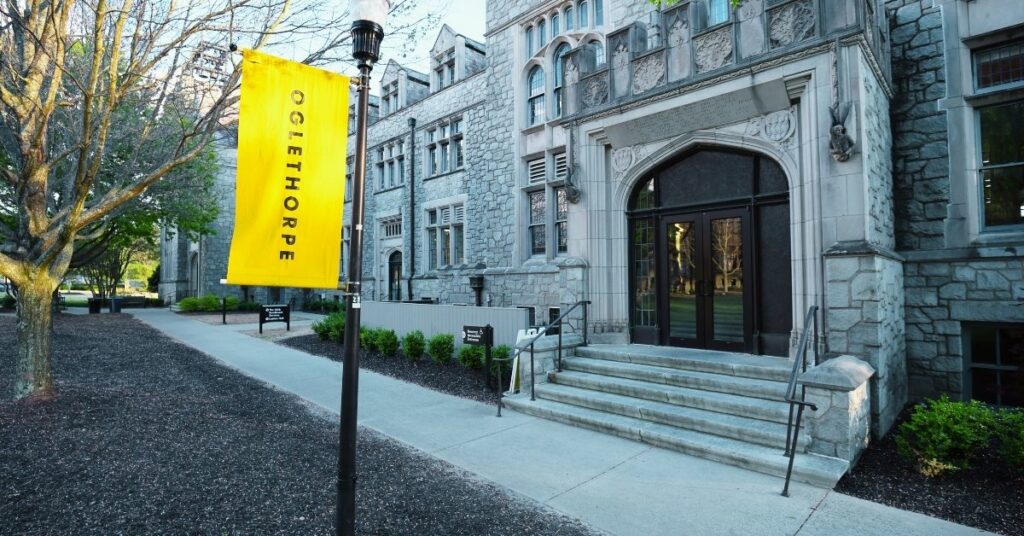 A yellow pole banner that reads "Oglethorpe" in front of a graystone, Gothic building.