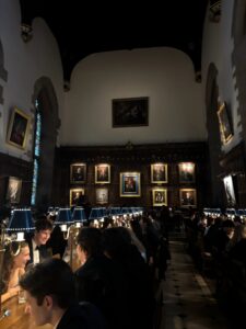 Students dressed in formal attire seated in a dining hall with dim lighitng. 