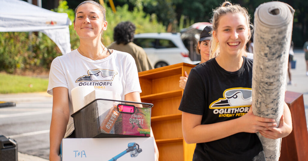 Students carry in boxes, rugs, and shelves on move-in day.