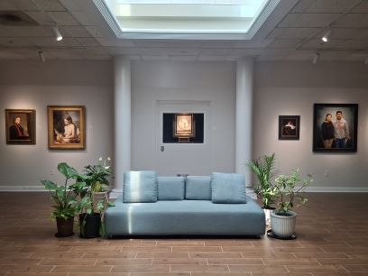 A couch between two potted plants in a museum gallery
