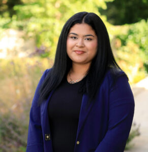 Young woman in blue blazer and black top.