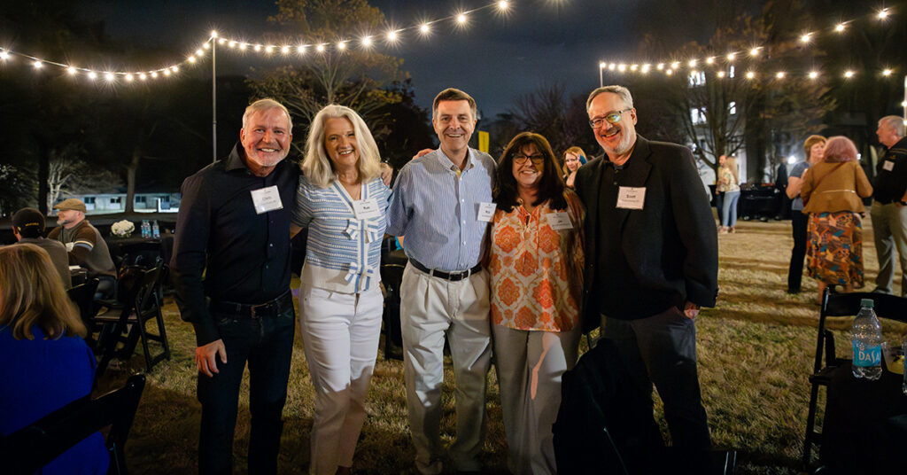 Alumni embrace under string lights during Stomp the Lawn at Alumni Weekend.