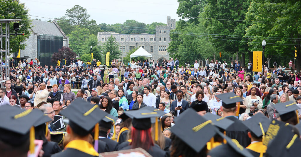 The academic quad is full of family and friends and graduates at Commencement.