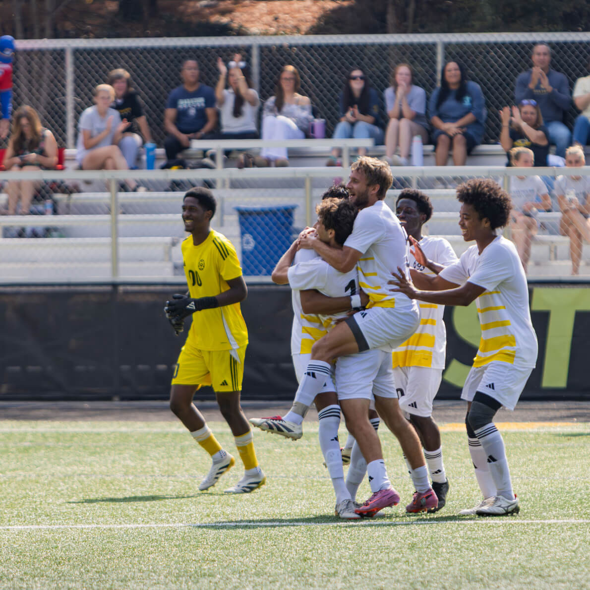 The men's soccer team celebrates on the turf field.