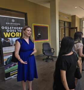 Staff member talks to a student with a banner behind her that reads "Oglethorpe Goes to Work."