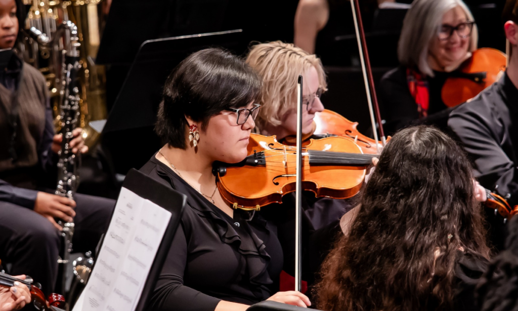 A musician in an ensemble playing the violin