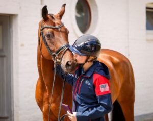 A horse rider gives a kiss to her horse's snout